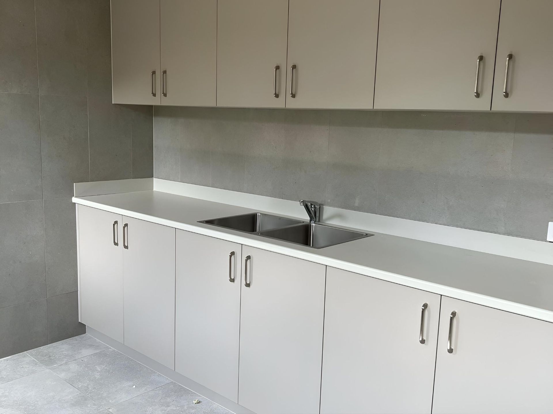 An Empty Kitchen with White Cabinets and A Sink — Inovative Interiors In Cardiff, NSW
