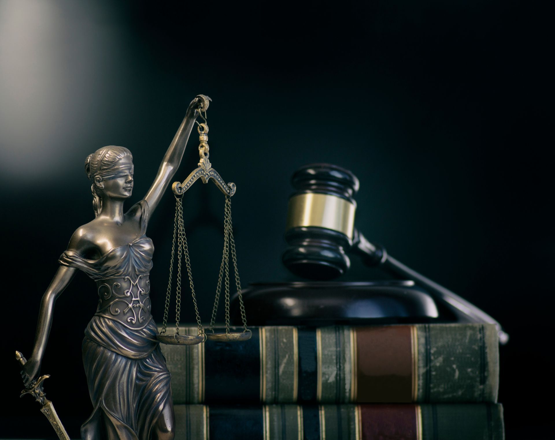 Law statue, gavel, and stacked law books on a dark desk