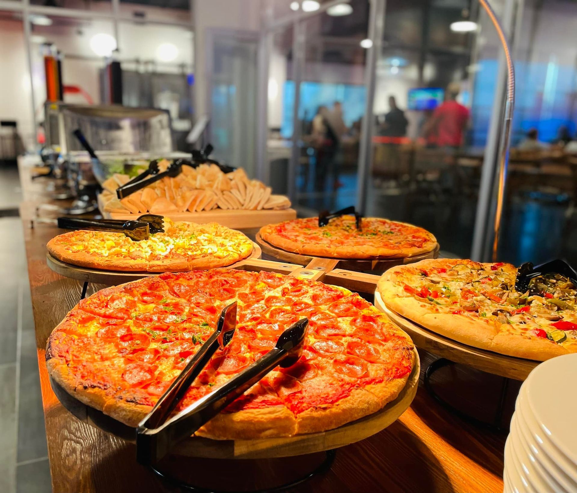 Pizza buffet with several large pizzas under warm lights in a restaurant serving area