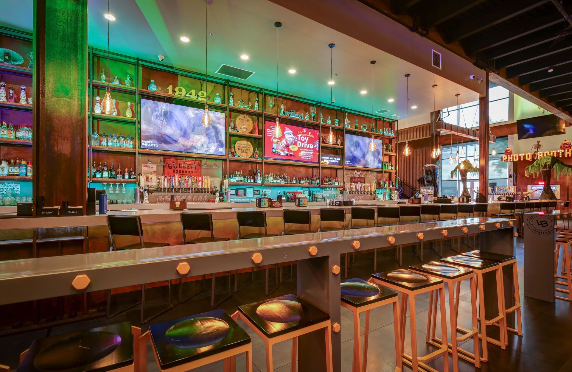 Modern bar interior with colorful backlit shelves, long counter, and stools