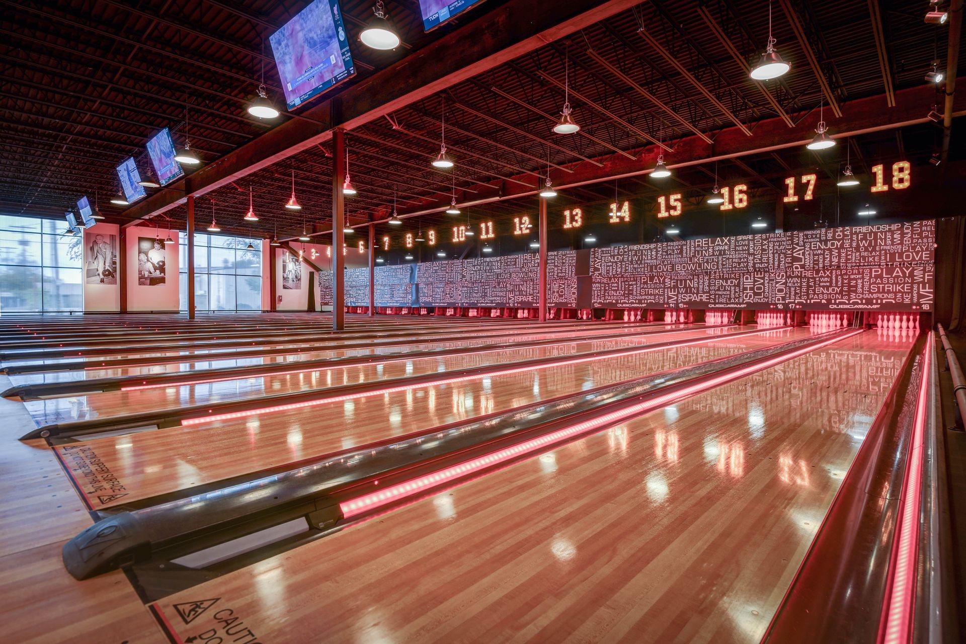 Empty bowling alley with polished wooden lanes and glowing lane numbers