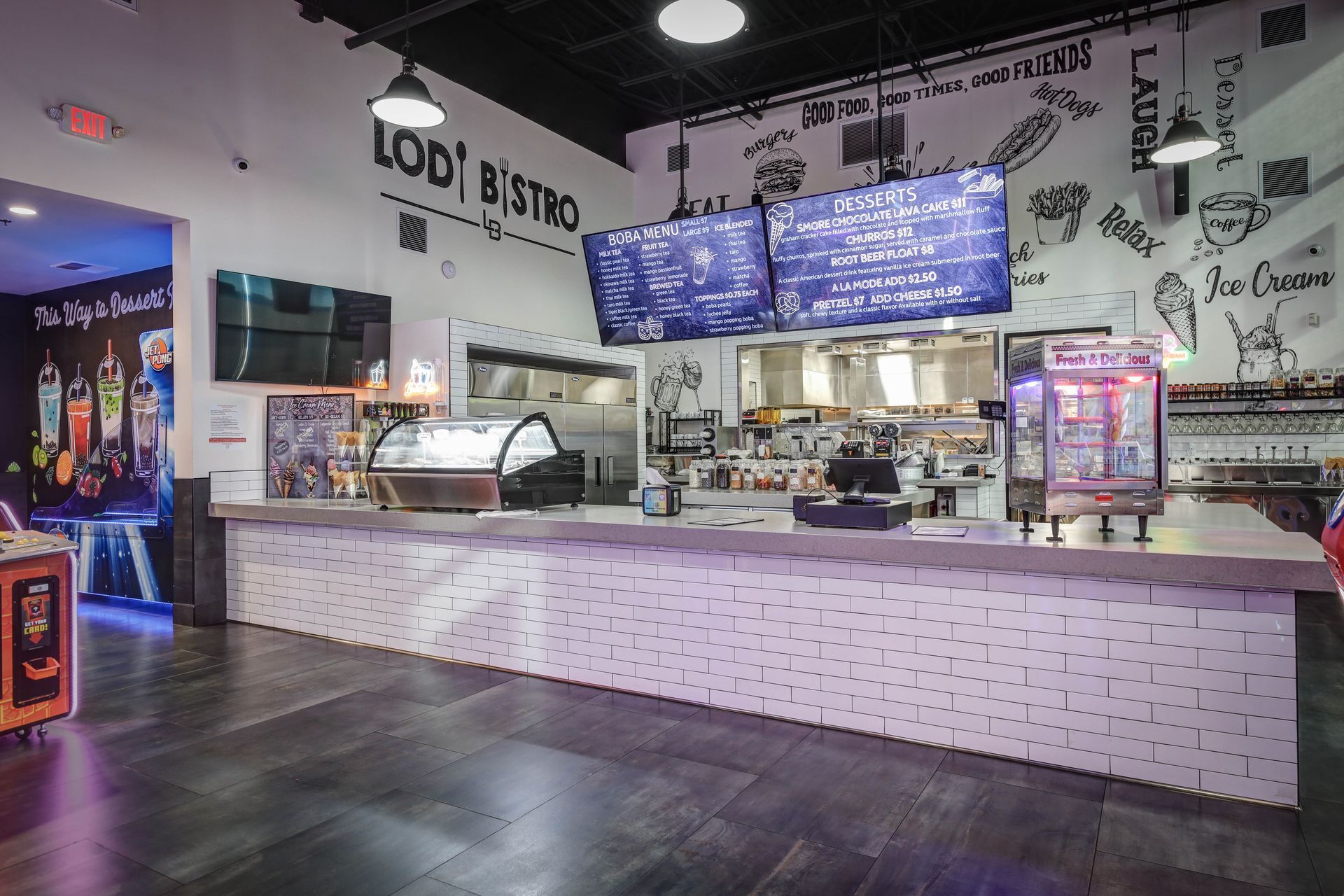 Modern dessert café counter with bright menu screens and pink-tiled front, viewed from the dining area