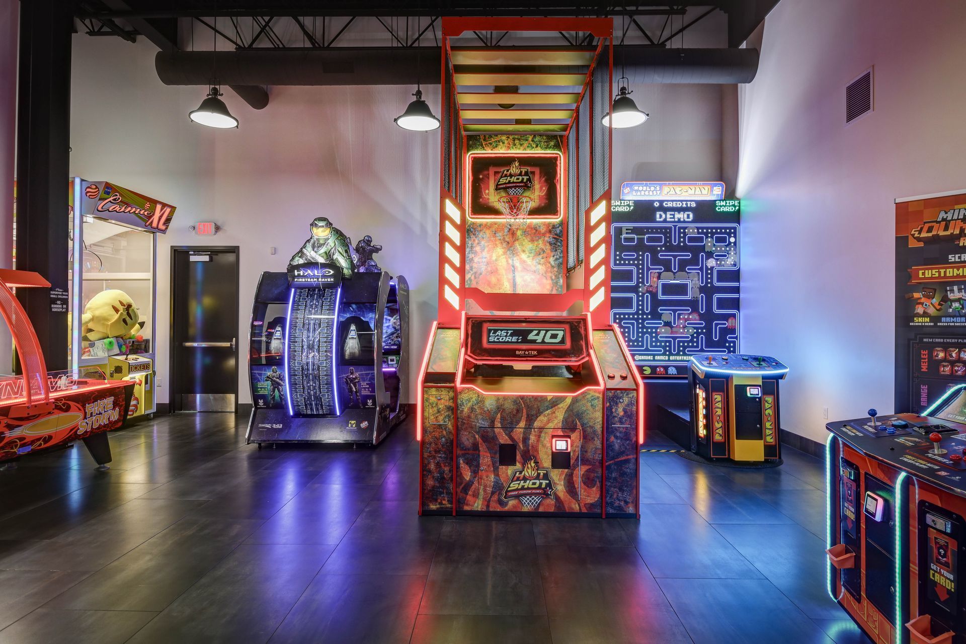 Arcade room with colorful game cabinets and glowing lights in a dim, modern space
