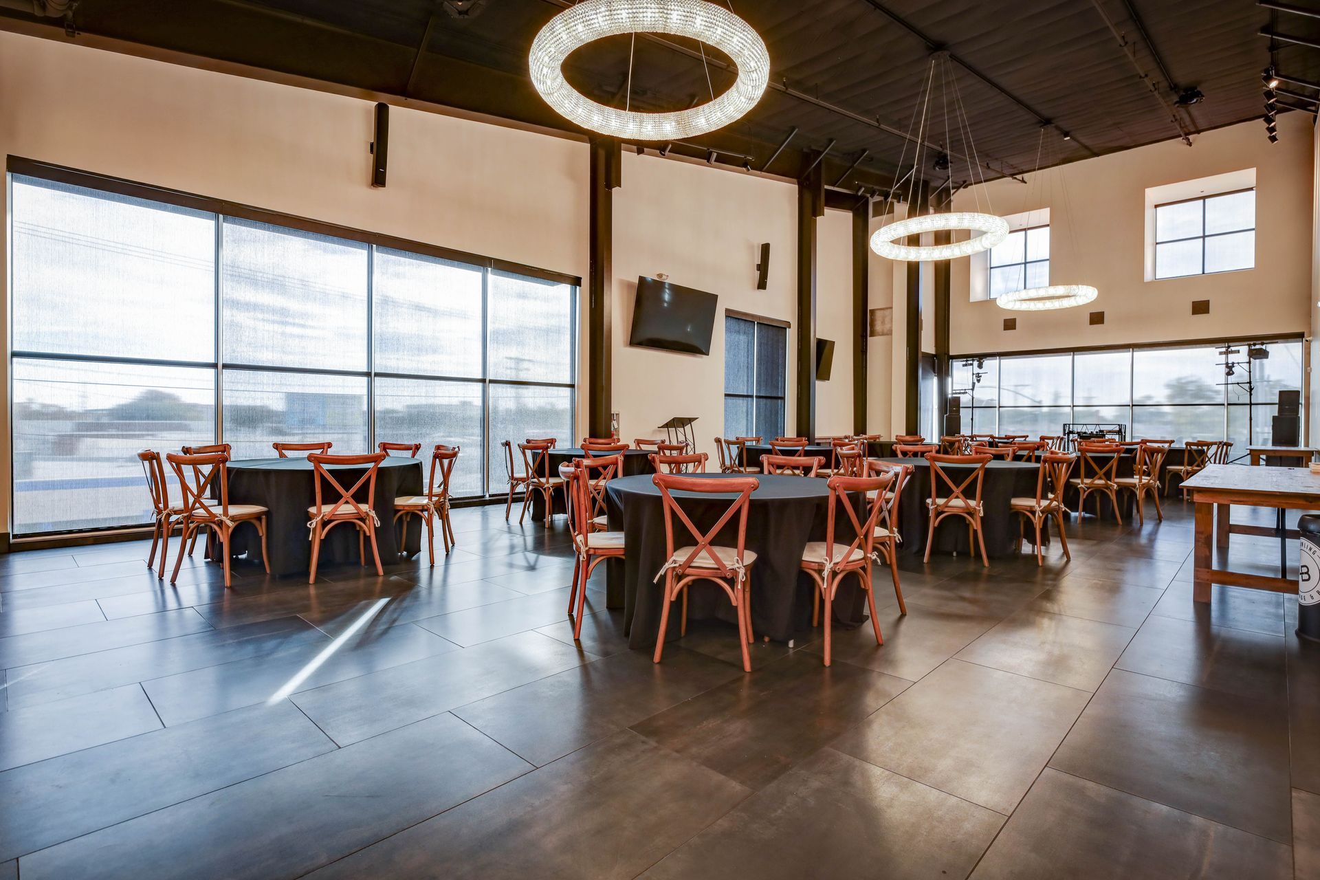 Bright, modern restaurant interior with wooden tables, chairs, and large windows overlooking the street