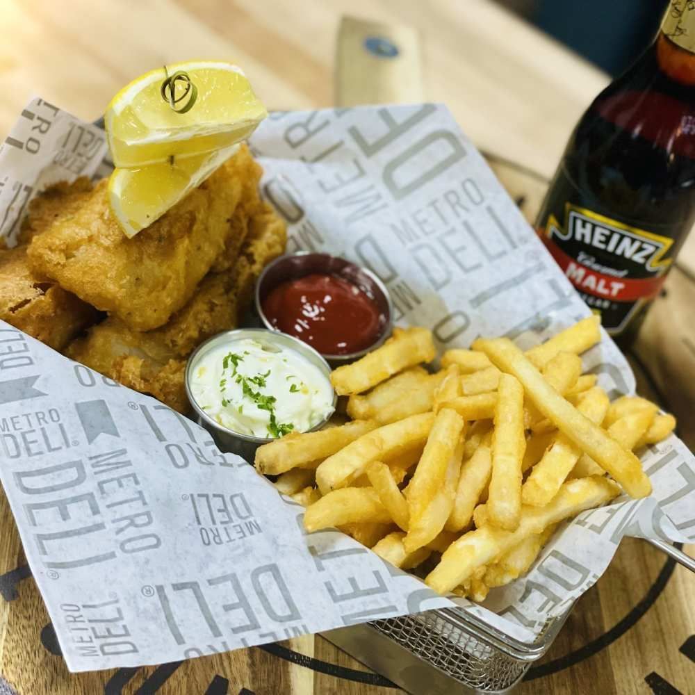 Fried chicken tenders and fries in a paper-lined basket with ketchup and dipping sauce