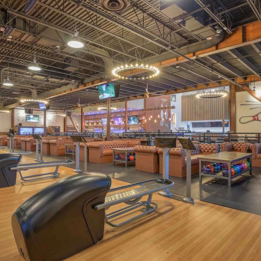 Bowling alley with lanes, seating, and bright overhead ring lights in a modern entertainment space