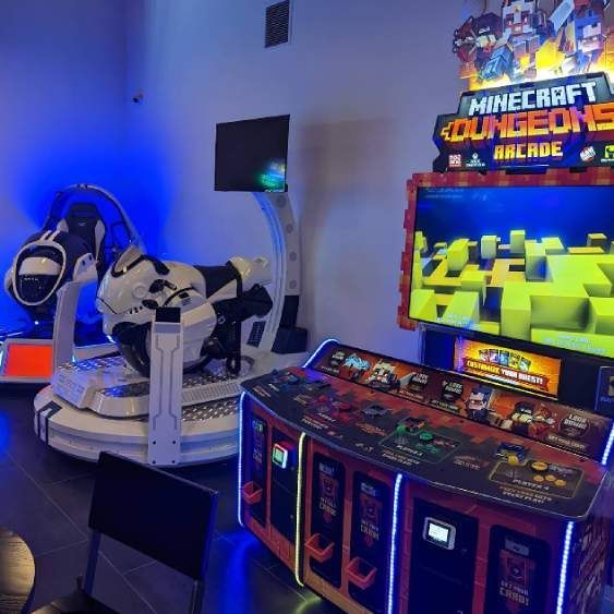 Arcade game area with a motorcycle simulator and a colorful Minecraft Dungeons machine