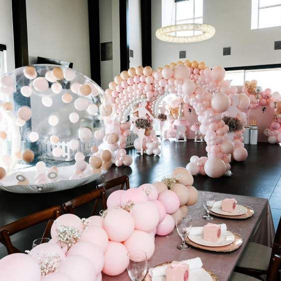 Pastel pink balloon arch and table settings in a bright event hall