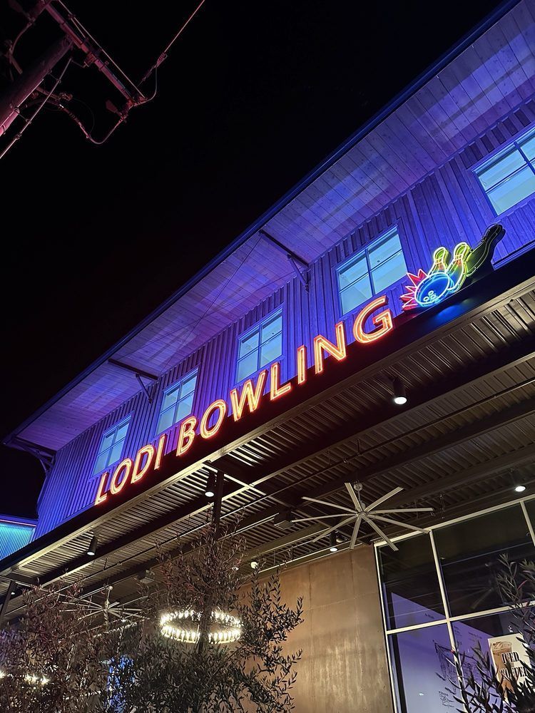 Neon-lit Lodi Bowling sign on a building at night under purple-blue lighting