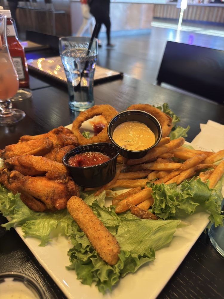Platter of fried appetizers with fries and dipping sauces on a restaurant table