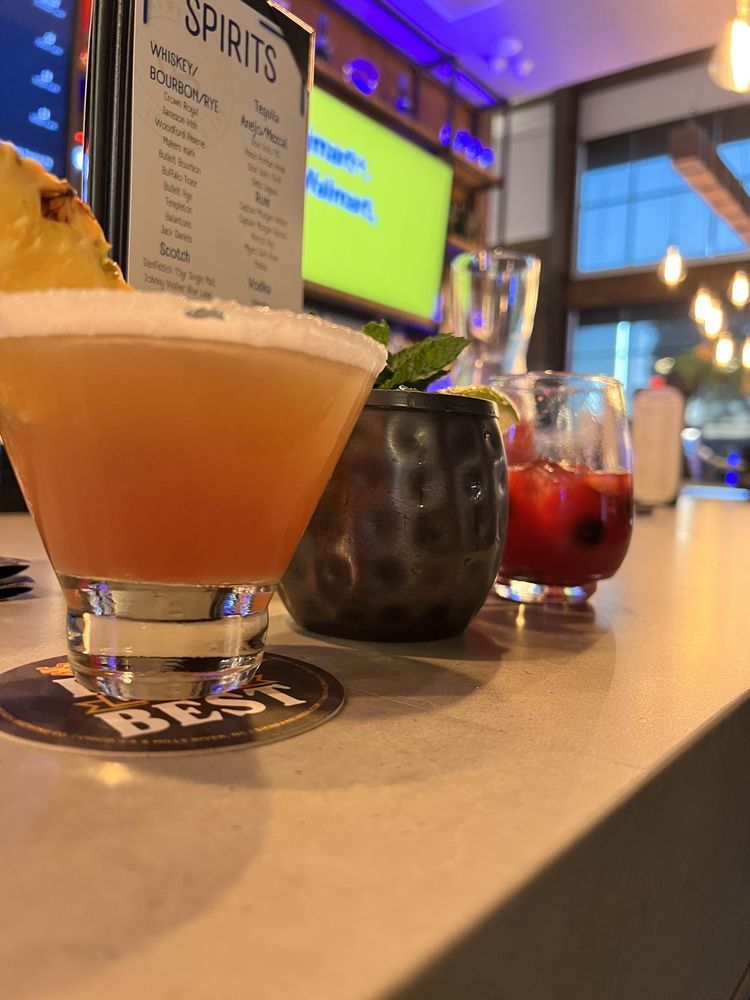 Three cocktails on a bar counter with a menu in the background
