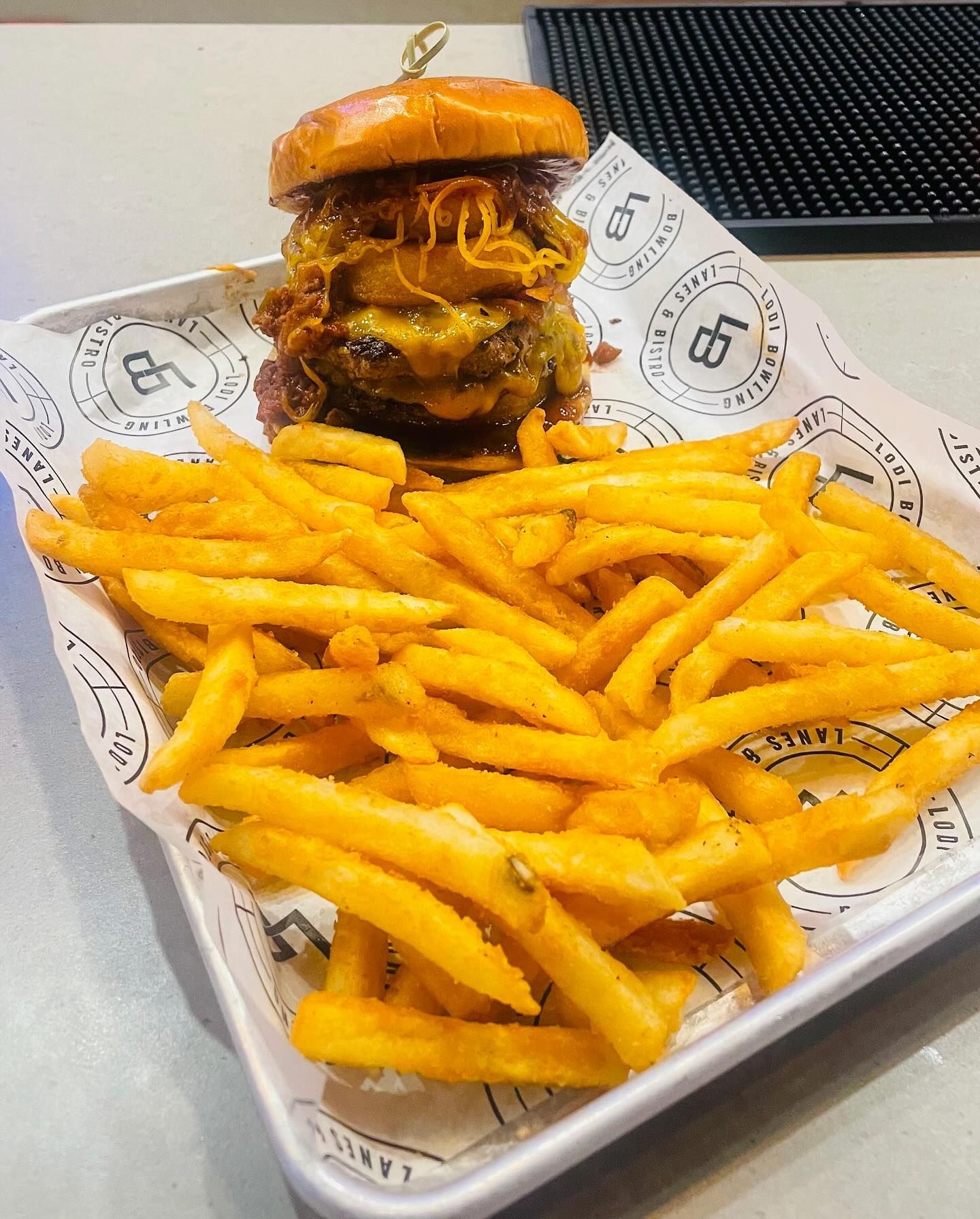 Cheeseburger with melted cheese and fries on a tray lined with branded paper