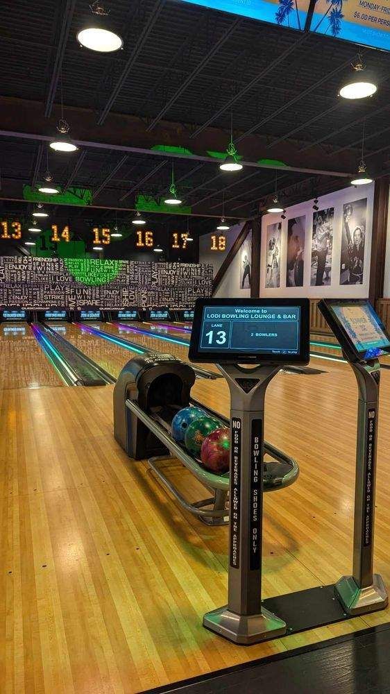 Bowling alley with polished lanes, glowing lane numbers, and a score monitor in the foreground