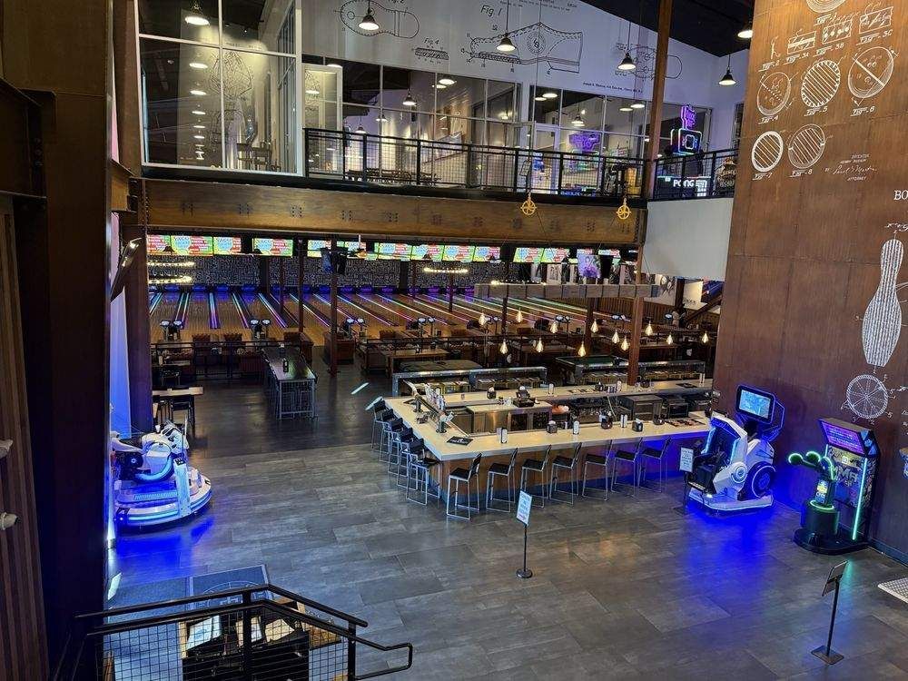 Empty bowling alley with lanes, tables, and blue arcade lights at night