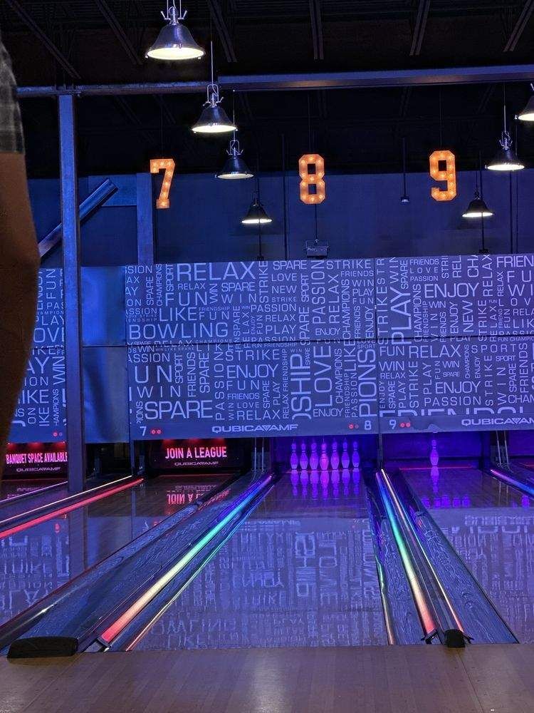 Empty bowling lanes in a neon-lit bowling alley with lane numbers 7, 8, and 9 overhead