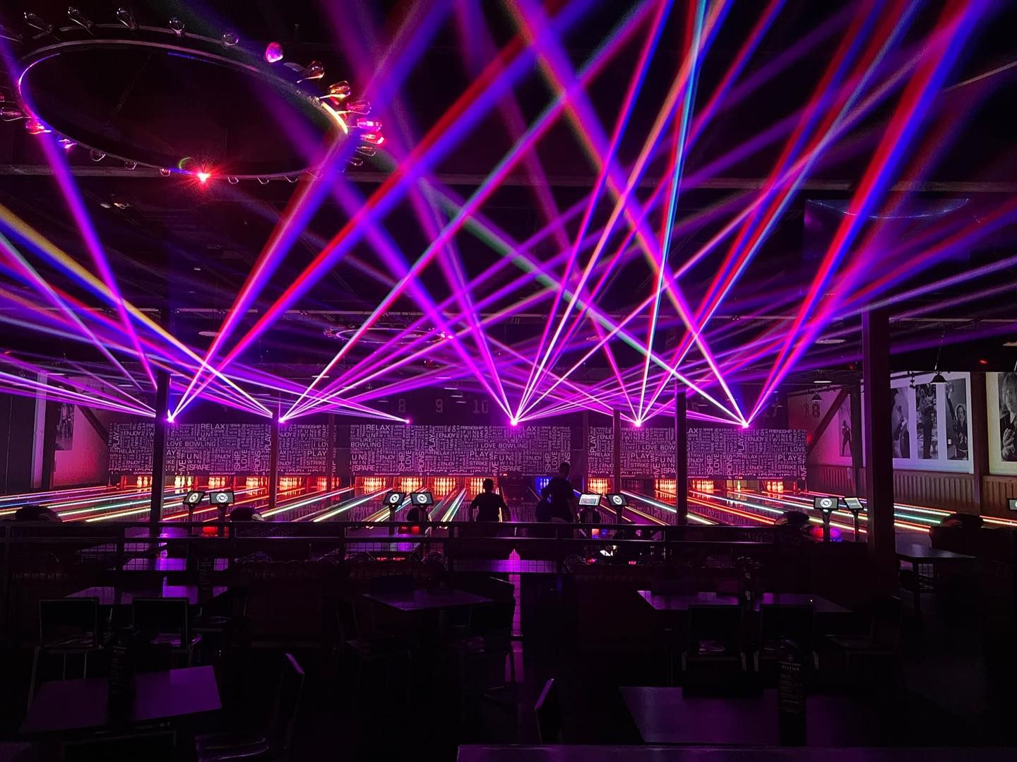 Nightclub with purple laser beams sweeping over a crowded dance floor and tables