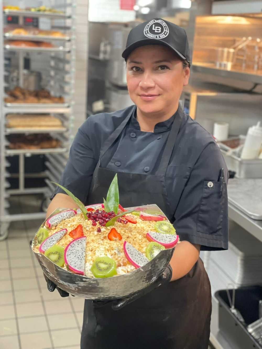 Chef holding a colorful pizza tray in a commercial kitchen