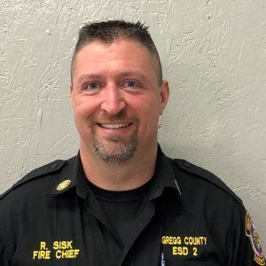 A man in a fire chief uniform is smiling for the camera.