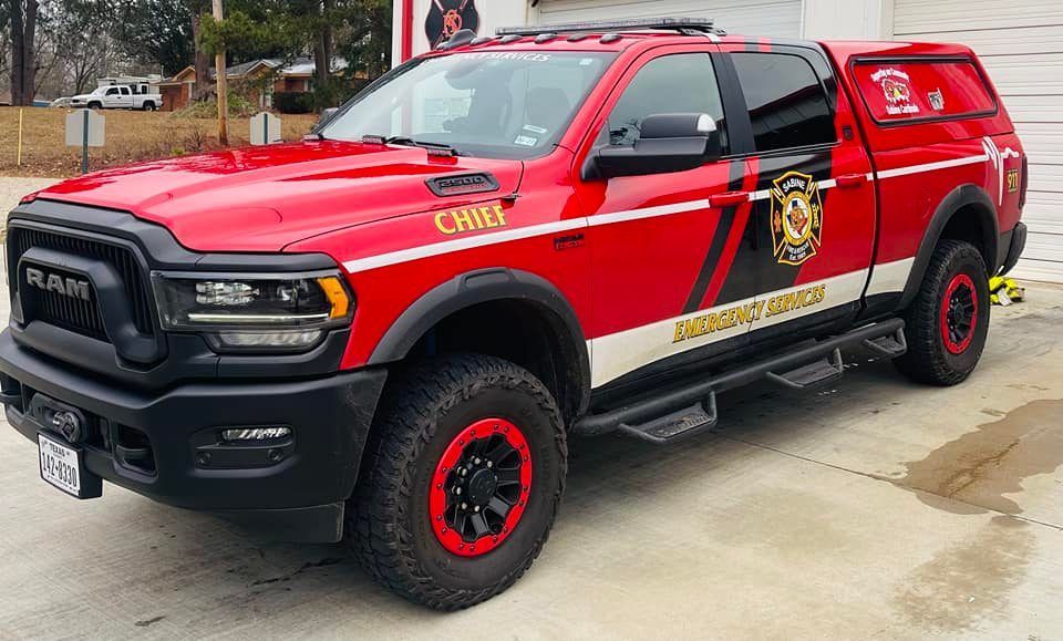 A red Fire Chief's truck is parked in front of a fire station.