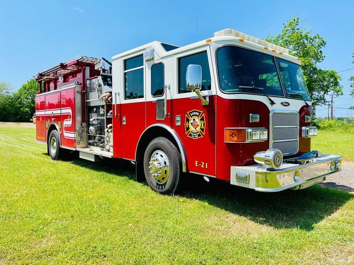 A red and white fire truck is parked in a grassy field.