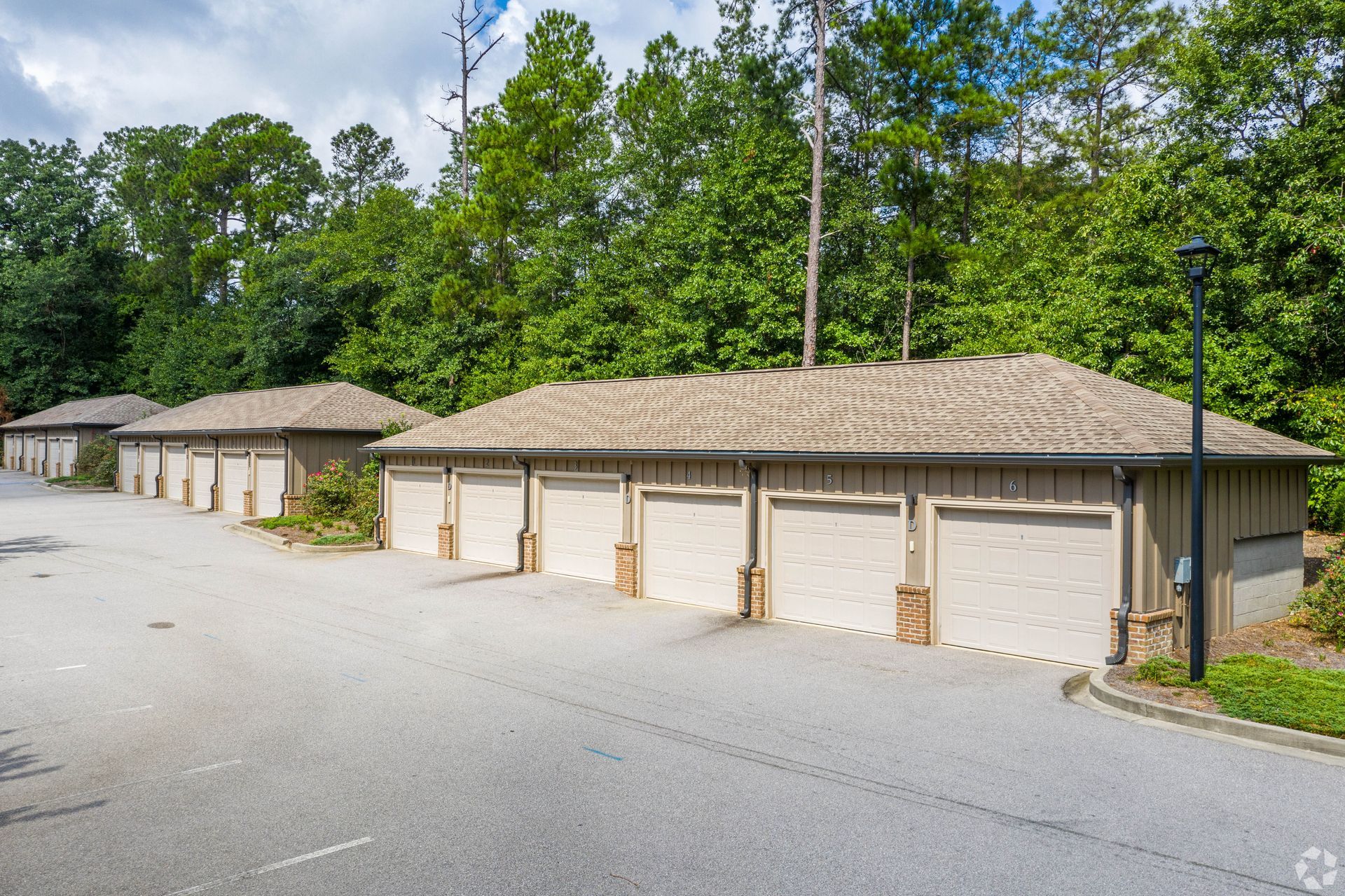 Row of beige garages with textured roofs, trees in background at Arcadia's Edge in Columbia, SC.