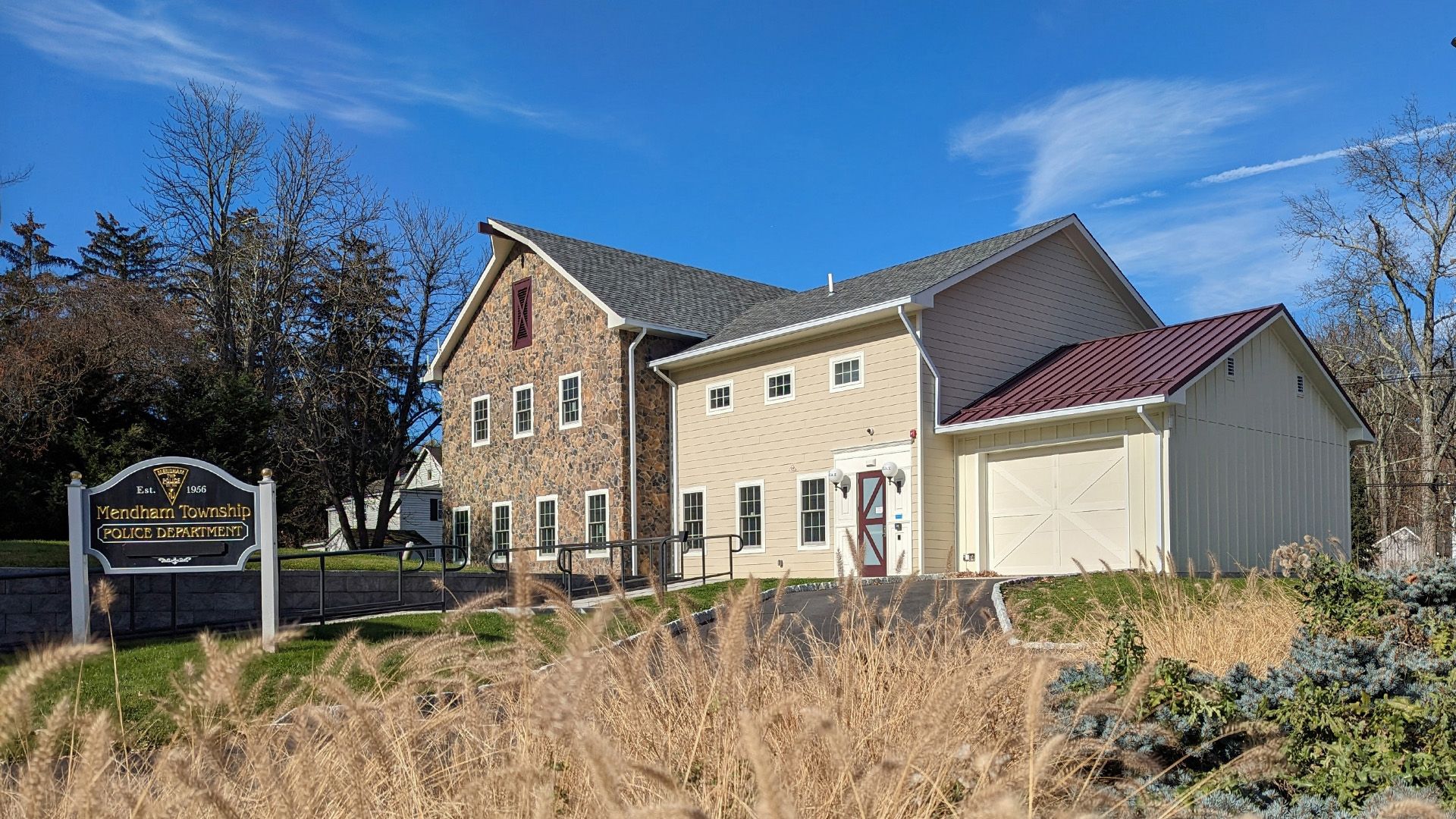 A multi-level building with stone and beige siding under a blue sky, featuring a prominent sign near the foreground.