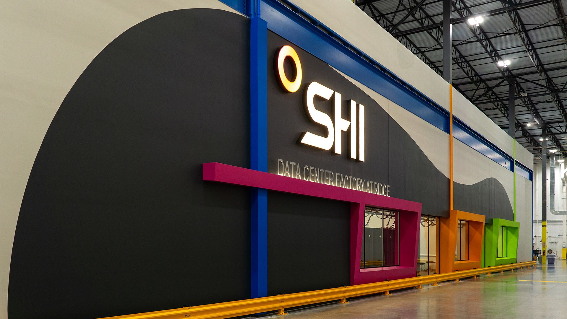An interior view of a warehouse featuring a large wall with the SHI logo and colorful architectural accents.