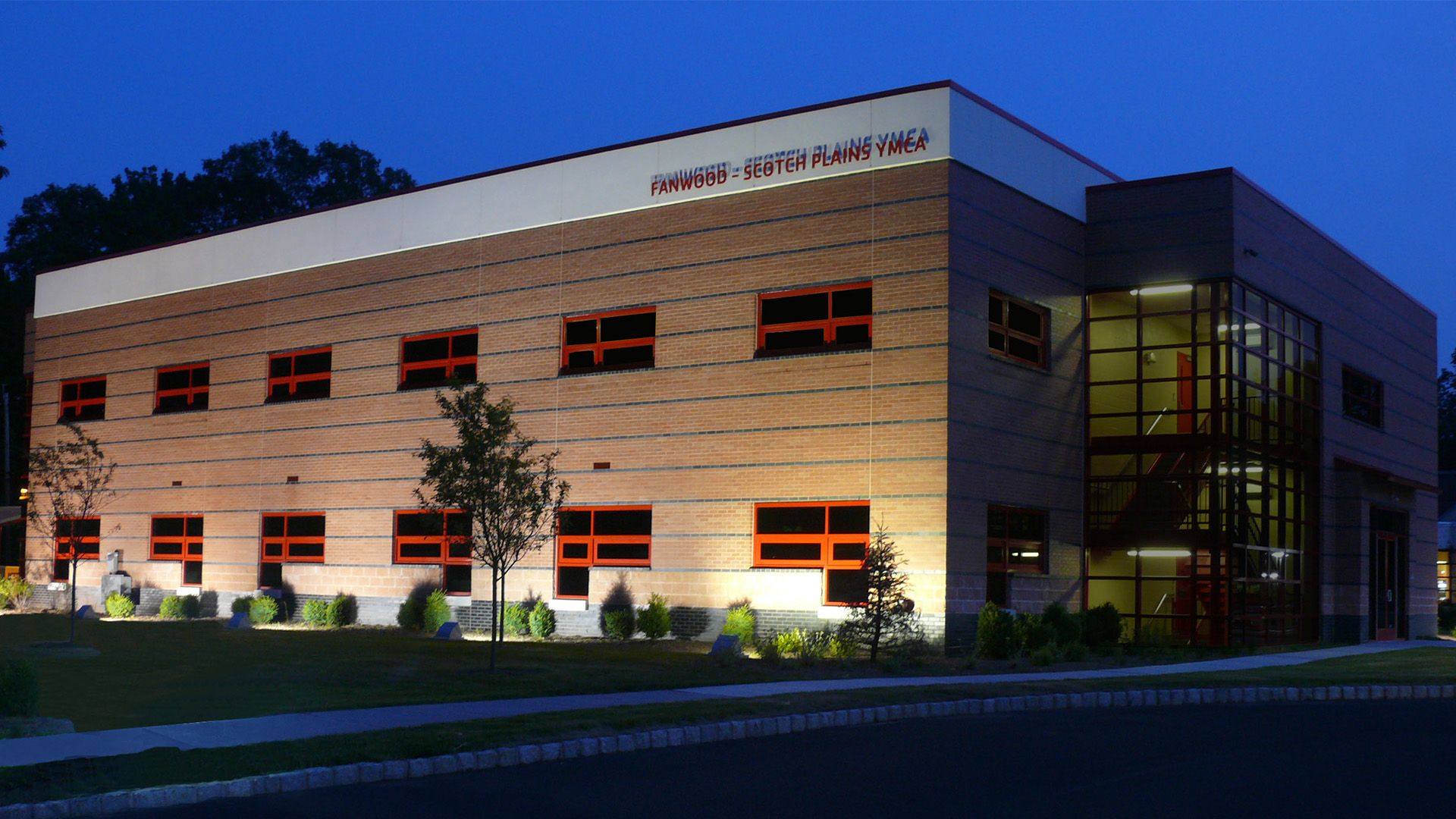 A two-story commercial building with horizontal wood-paneled siding, rectangular windows, and a glass-enclosed stairwell.