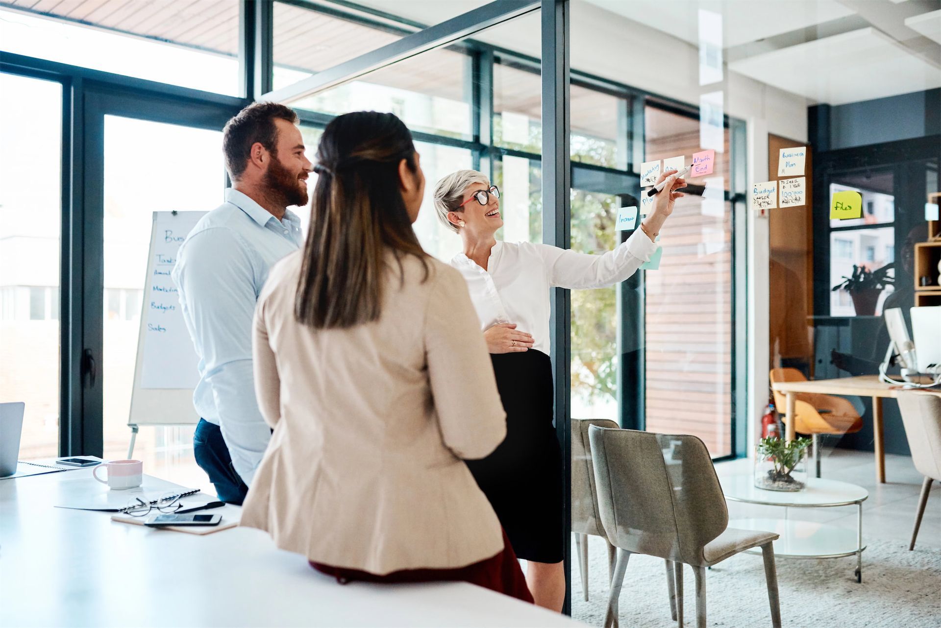 A group of colleagues in a bright office consults documents on a table as a professional points to a paper.