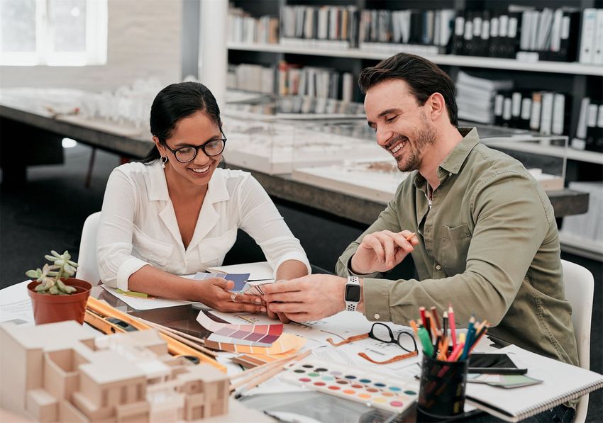 A diverse professional team collaborating in a bright office, with one person pointing at documents on a table.