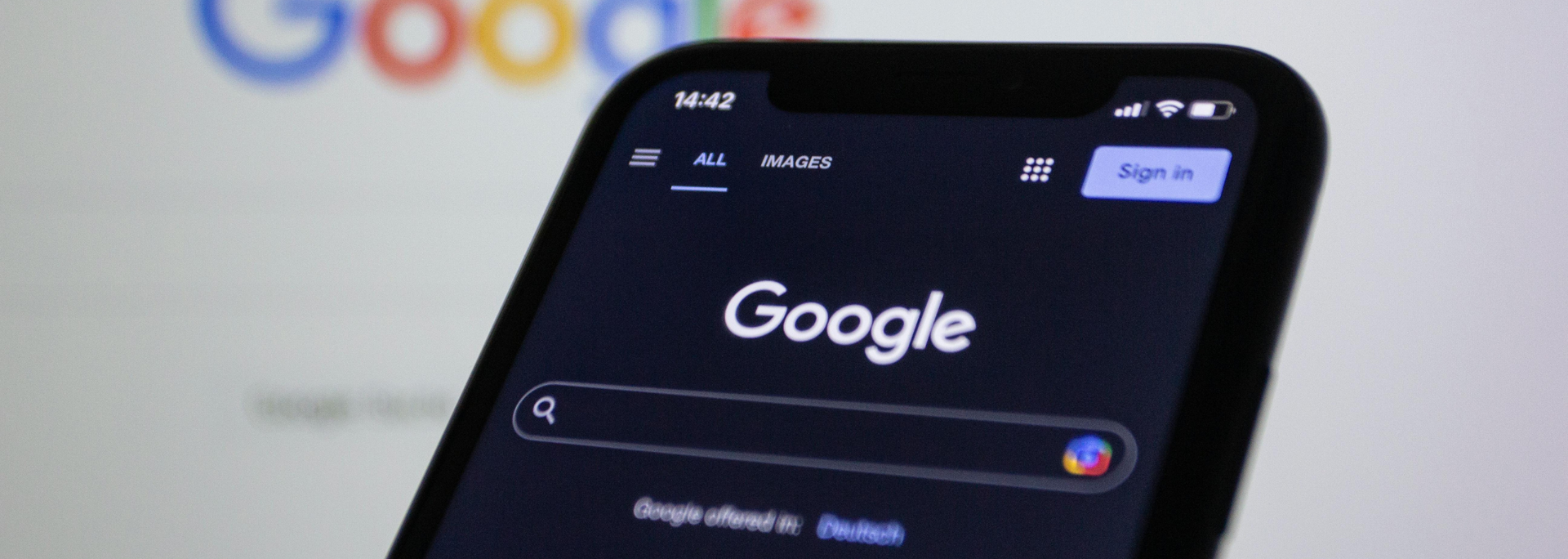 Close-up of a smartphone displaying the Google search homepage in dark mode