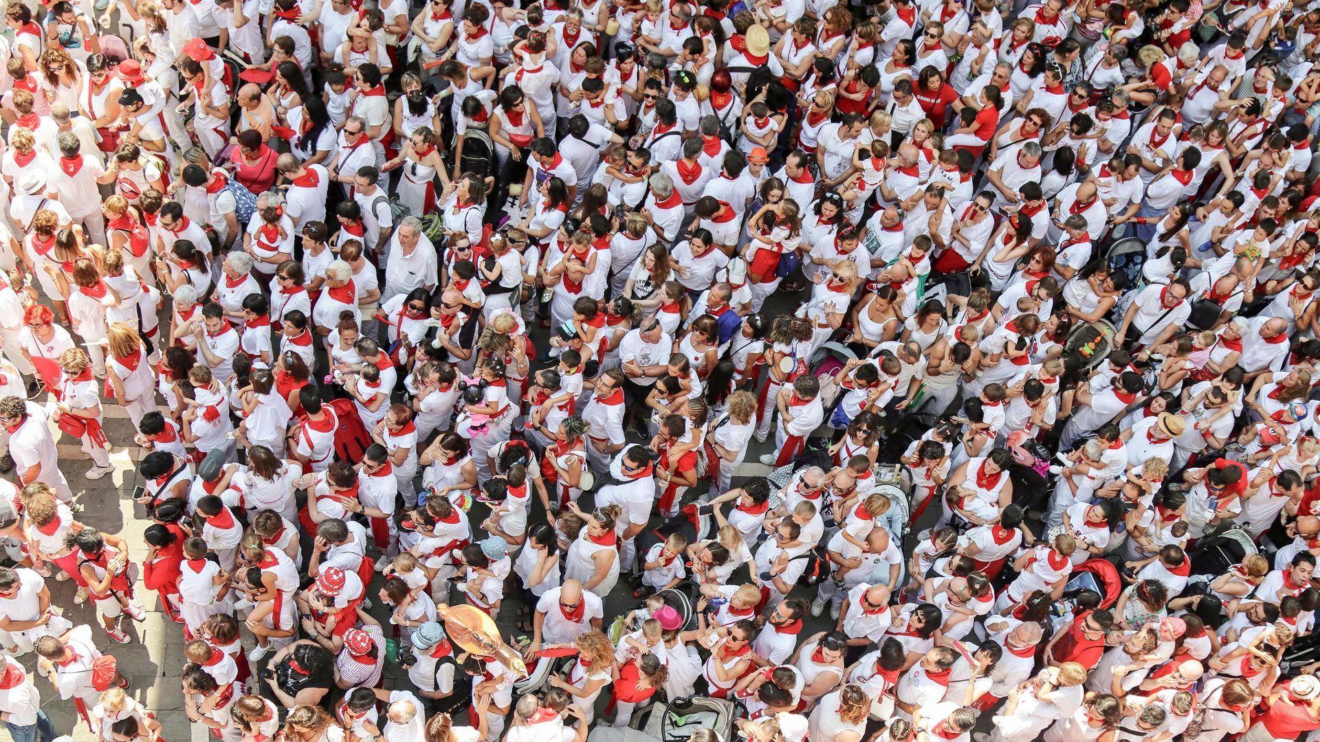 Crowd of people in white and red shirts packed together in a public gathering
