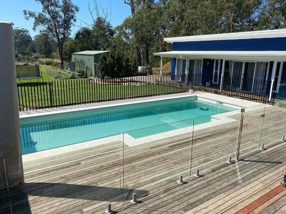 A Large Swimming Pool Is Surrounded By A Fence And A Wooden Deck — Solitary Island Pools In Coffs Harbour, NSW