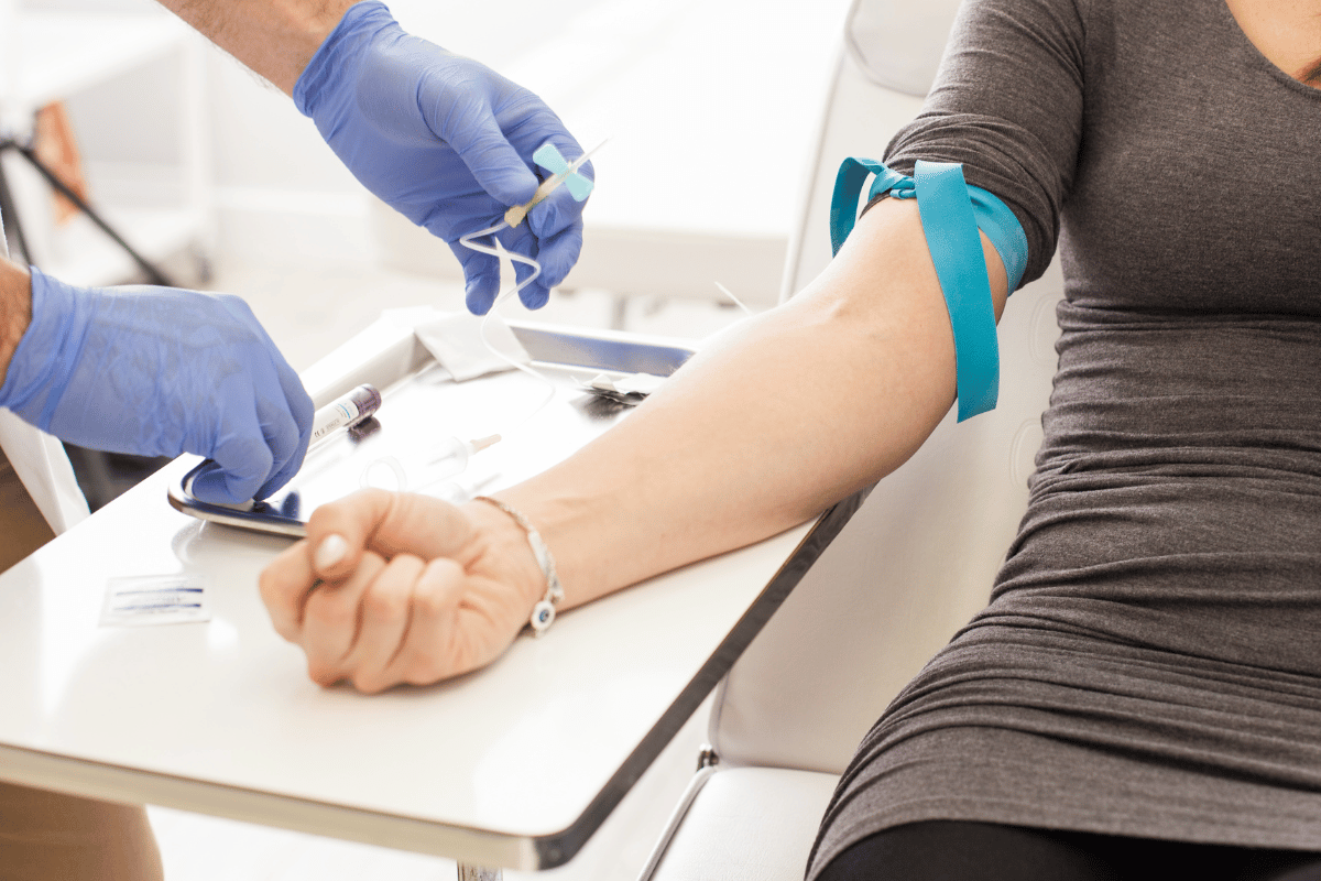 Gloved healthcare worker drawing blood from a patient’s arm in a clinic