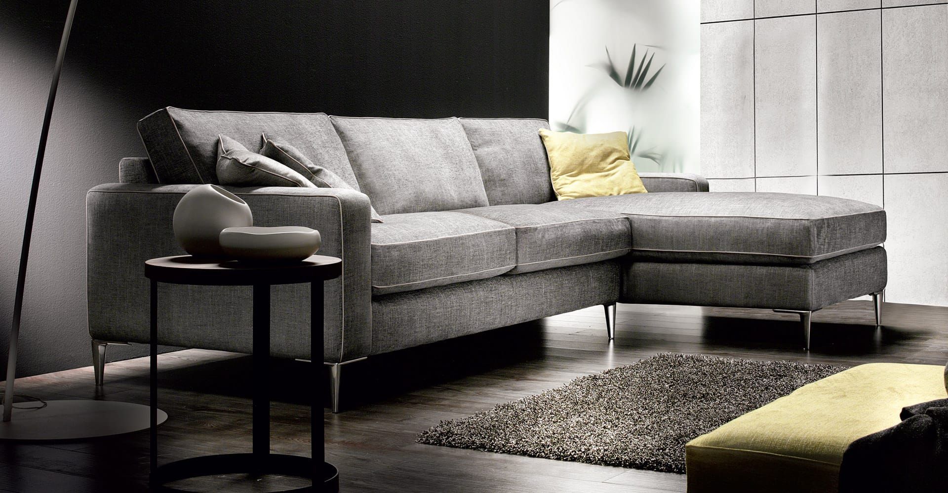 Moderno divano componibile grigio con dettagli gialli in un elegante soggiorno.