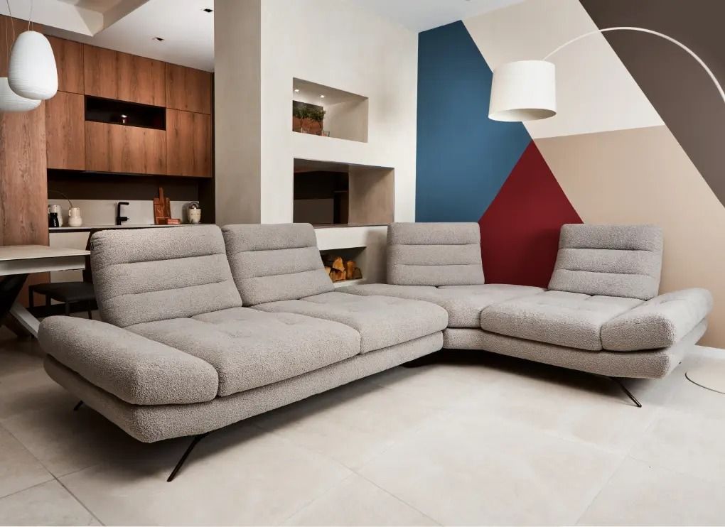 Soggiorno moderno con divano componibile beige, quadri geometrici alle pareti e scaffalature in legno integrate.
