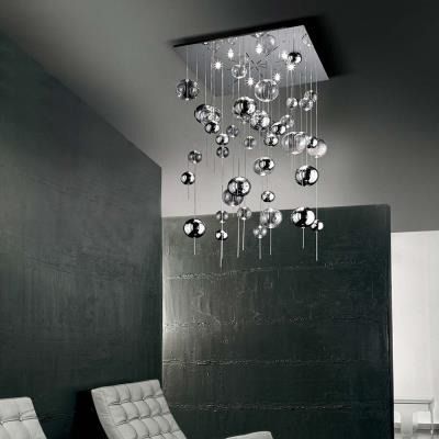 Interni moderni neri con lampadario a sfera cromato sospeso sopra sedute grigie.