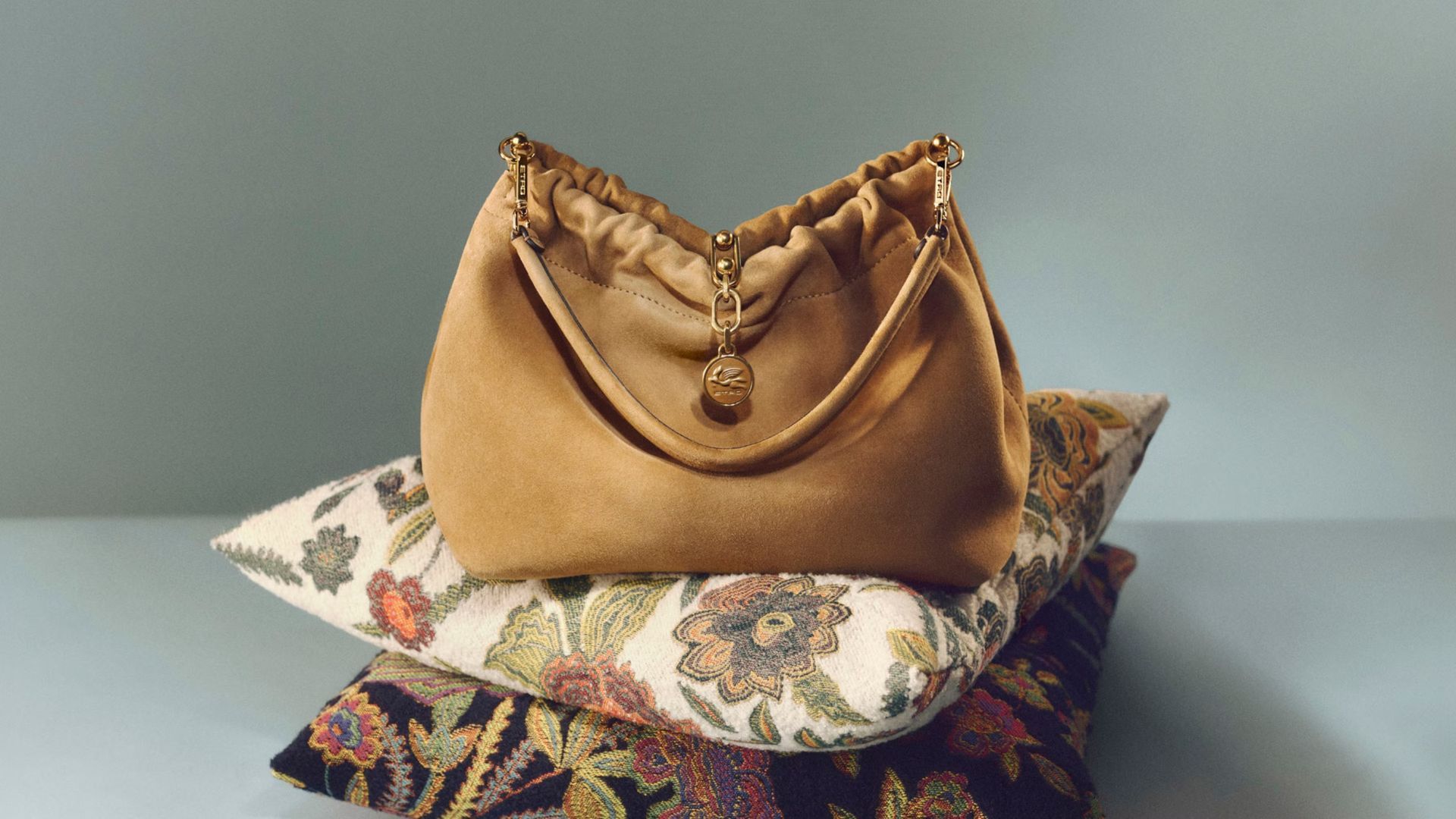 Pochette dorata su cuscini impilati a fantasia su sfondo grigio