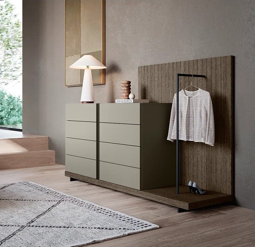 Camera da letto moderna e minimalista con comò color salvia, lampada da terra e appendiabiti in legno con una camicia a righe.