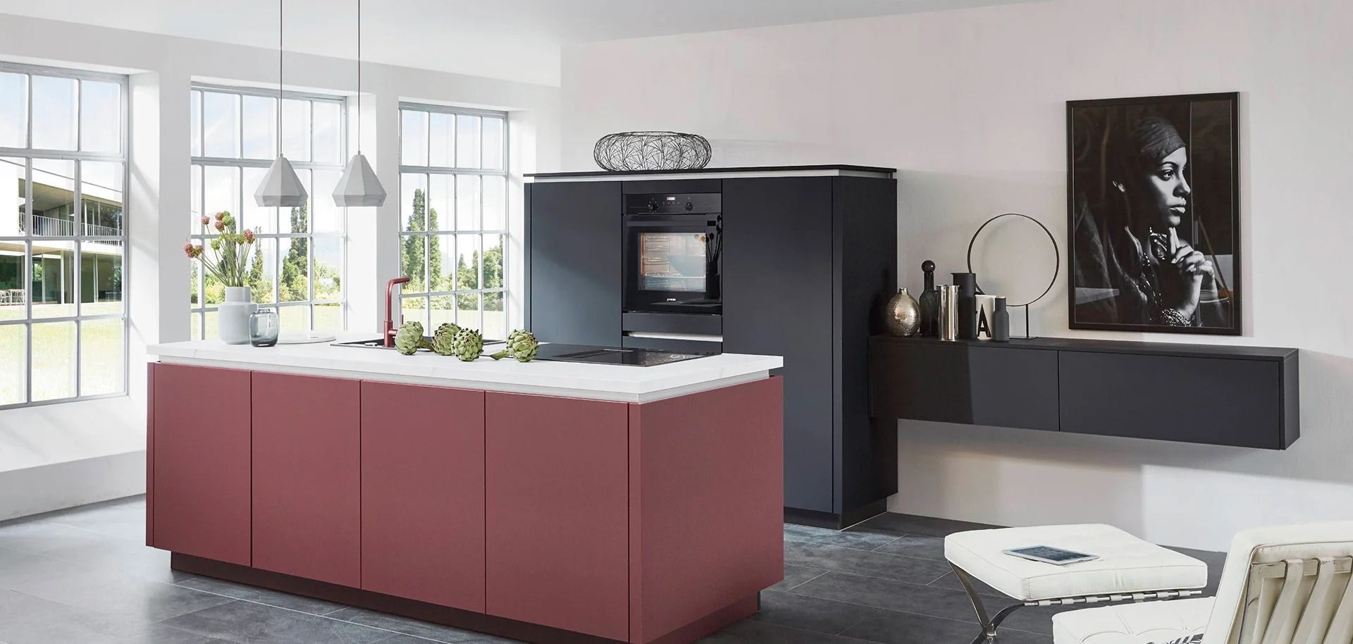 Cucina moderna con mobili bianchi, isola rossa, frigorifero nero e consolle a muro grigia per riporre gli oggetti.