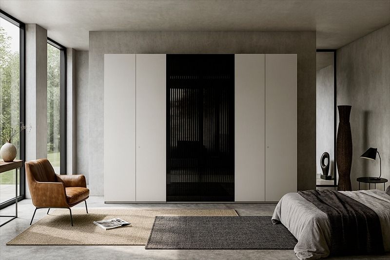 Camera da letto moderna e minimalista con armadi bianchi, ampia finestra, poltrona e letto.