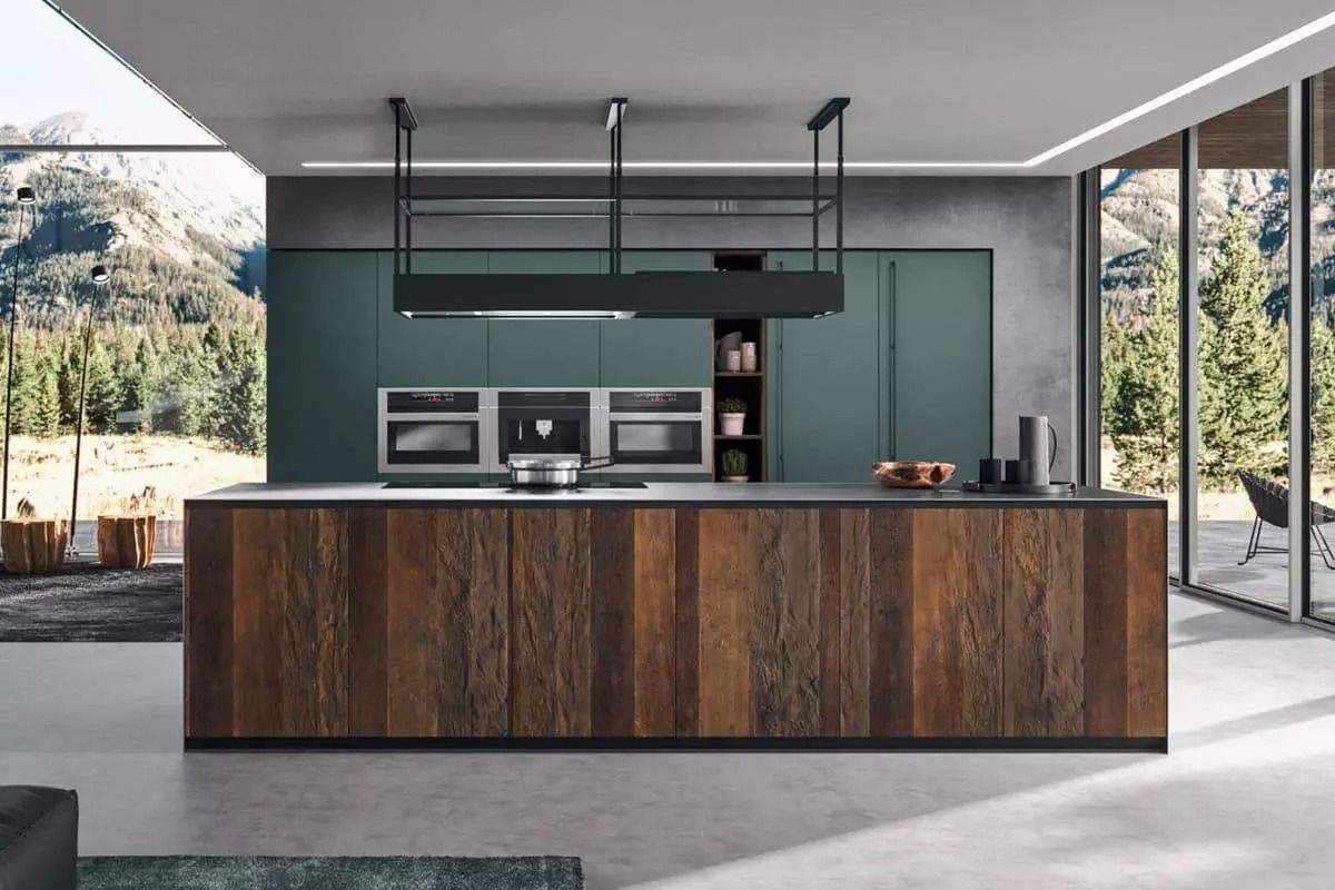 Cucina moderna con isola in legno, elettrodomestici a incasso e finestre a tutta altezza con vista sul verde.