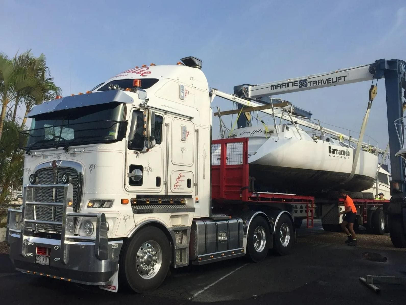 A Large White Semi Truck Is Carrying a Boat on A Trailer — Smillie Transport Pty Ltd in Mackay, QLD