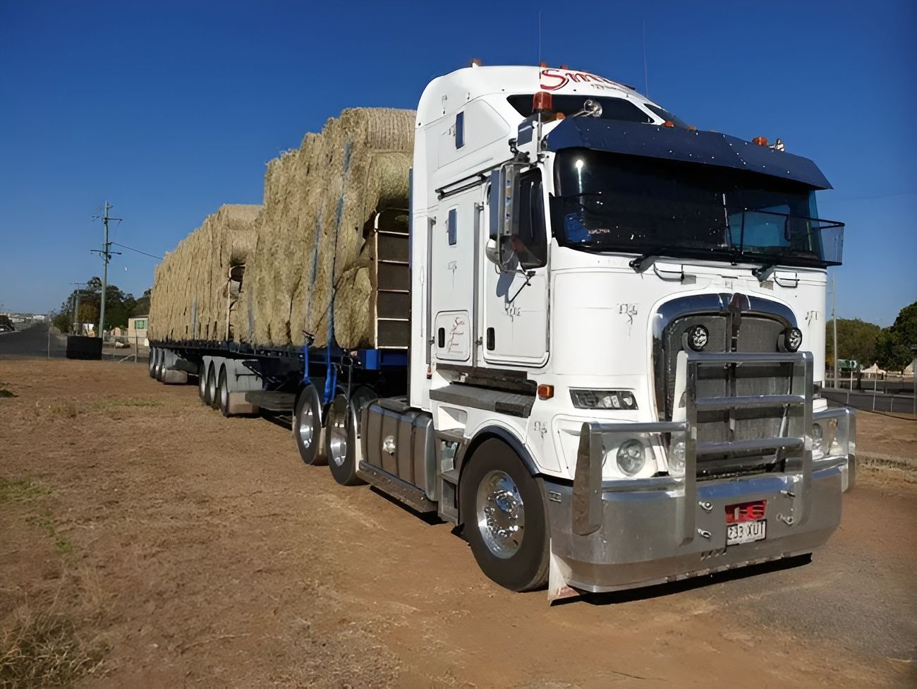 A Semi Truck with A Tarp on The Back Is Driving Down a Curvy Road — Smillie Transport Pty Ltd in Two Mile, QLD