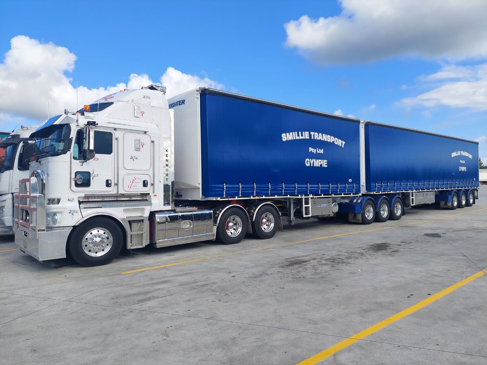 A White Semi Truck Is Driving Down a Highway at Sunset — Smillie Transport Pty Ltd in Mackay, QLD