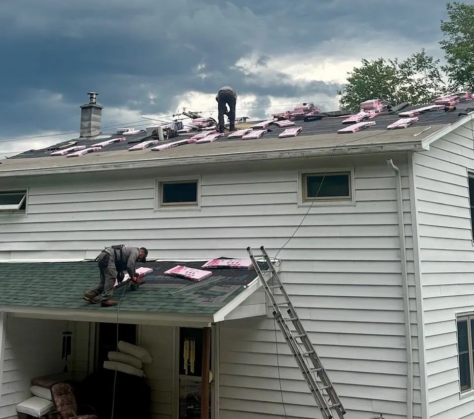 Storm-damaged asphalt shingles on a residential roof showing cracked and lifted shingles under an overcast winter sky