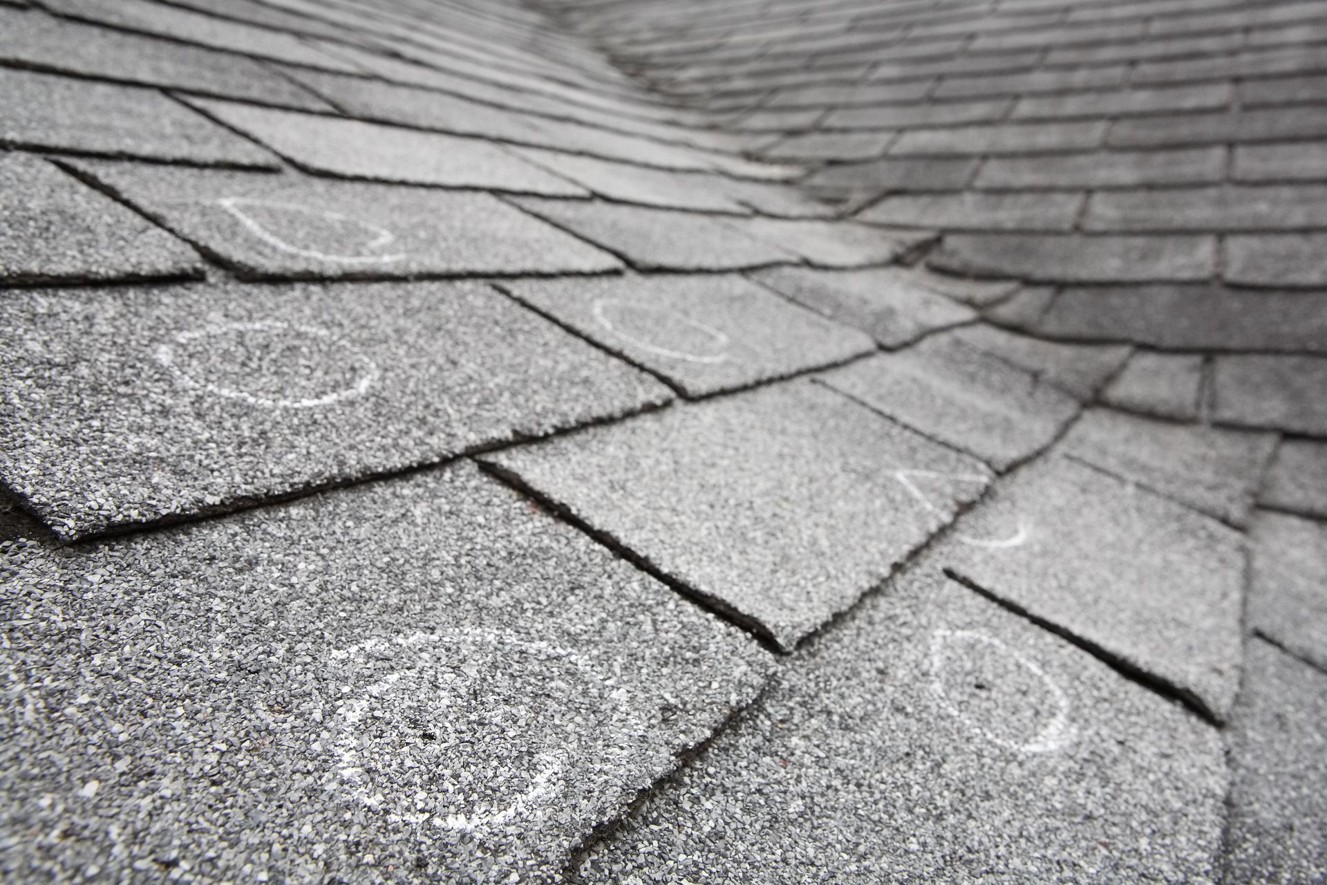 Close-up of gray asphalt shingle roof with visible hail damage: circular indentations.