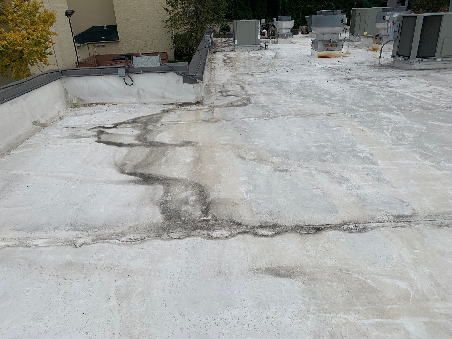 Flat rooftop with discoloration and staining; industrial building background.