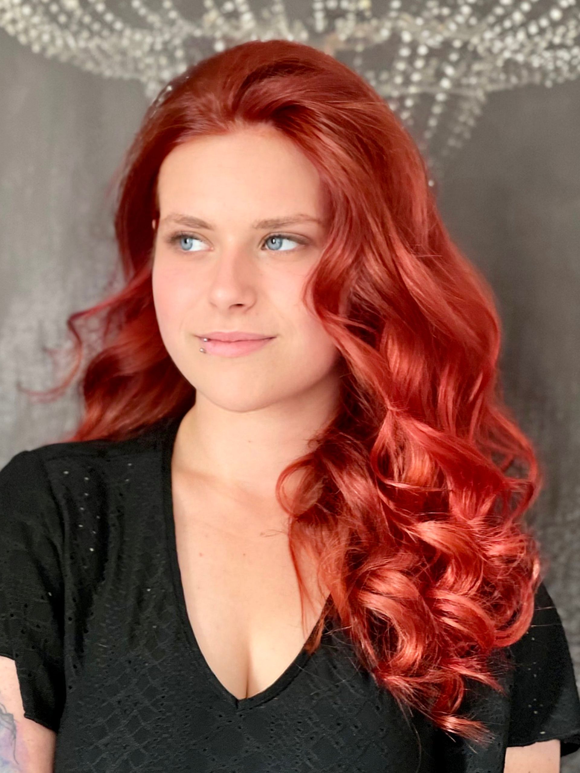 Eine Frau mit langen roten Haaren trägt ein schwarzes Hemd.