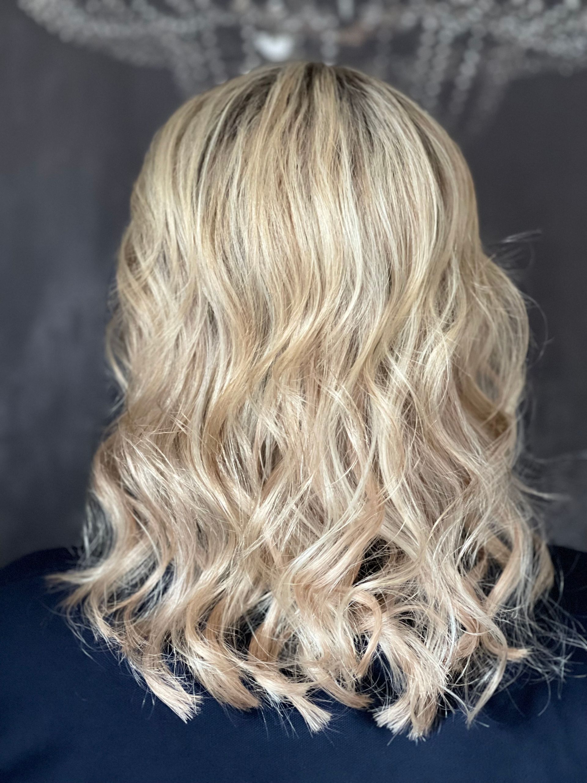 Eine Frau mit blondem, lockigem Haar trägt ein blaues Hemd.